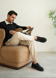 Man reading a magazine on a beige armchair in a minimalistic room.
