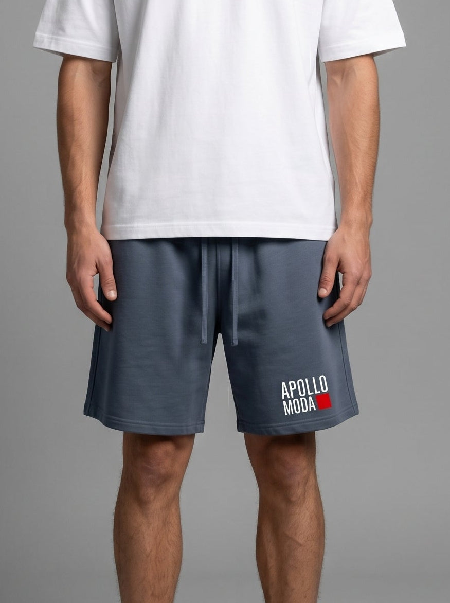 Man wearing a white t-shirt and dark shorts with a logo on a gray background