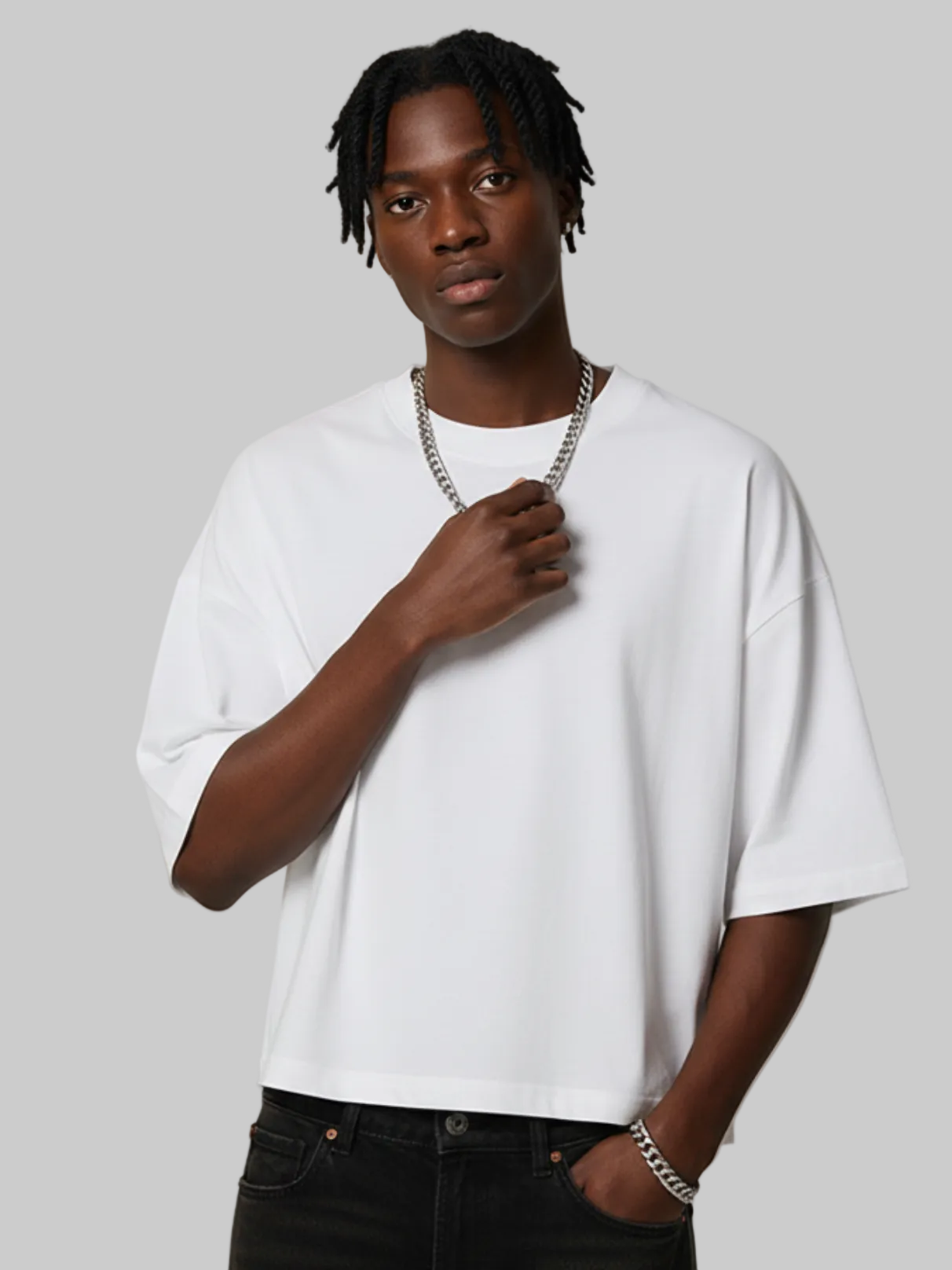 Aero boxy crop tee in white by Apollo Moda, worn with black pants on a grey background